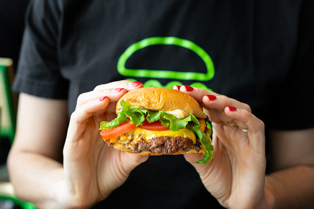 Shake Shack employee holding a hamburger