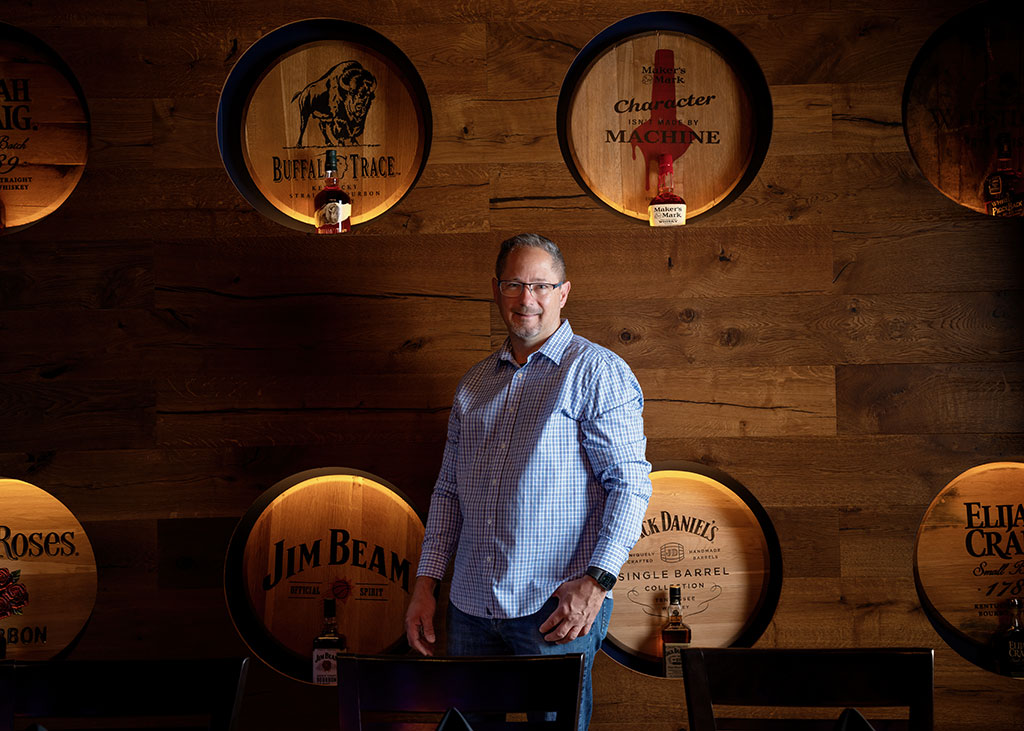 Operating Partner Steve Parker proudly poses in front of the iconic whiskey barrel wall at the newest location of the Federal American Grill in Scottsdale, AZ